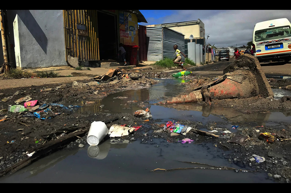 Sewage runs down a street in Dunoon, a township in Cape Town. Sewage spillages and overflows are rife in the area.  [Credit: dailymaverick.co.za | Peter Luhanga]