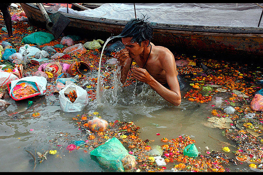 Taking a bath in sacred waters filled with trash. [Credit: gangaaction.org]